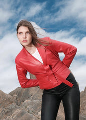 Woman wearing a red Leather Blazer jacket and black pants standing on rocky terrain with a blue sky.