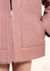 Close-up of a fuschiavleather hooded jacket with a zipper on a beige background