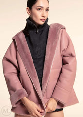 Woman wearing a fuschia leather hooded jacket with a neutral background
