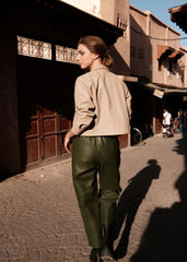 Woman walking on a street in an urban setting with buildings and people in the background.
