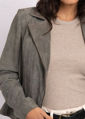 Woman wearing a gray suede jacket over a beige sweater on a white background