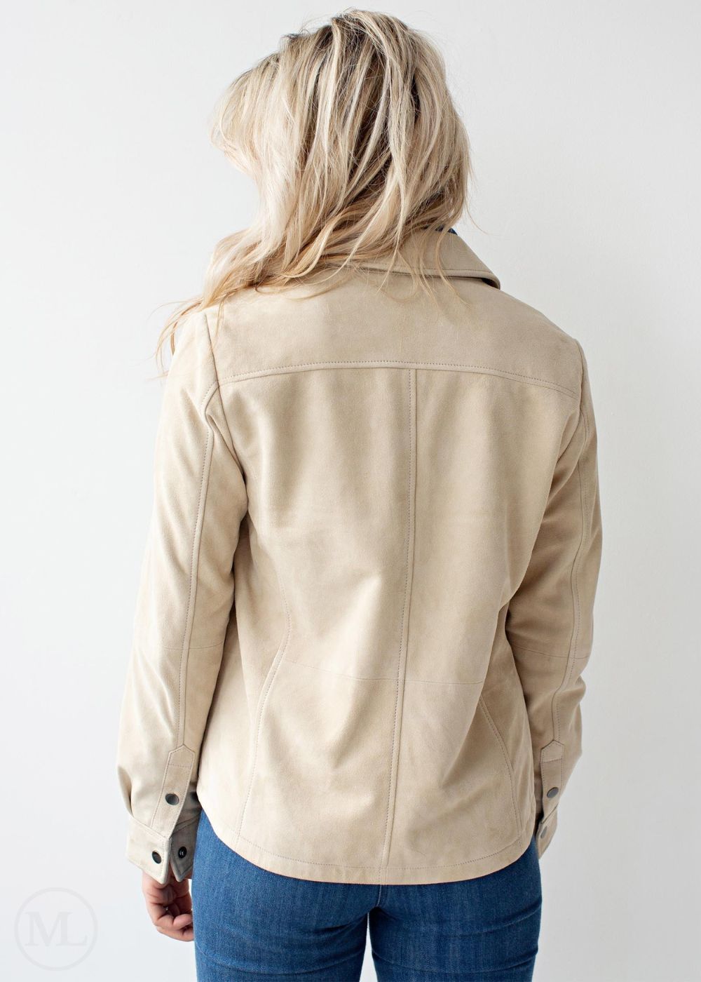 Woman wearing a off white jacket and blue jeans on a white background