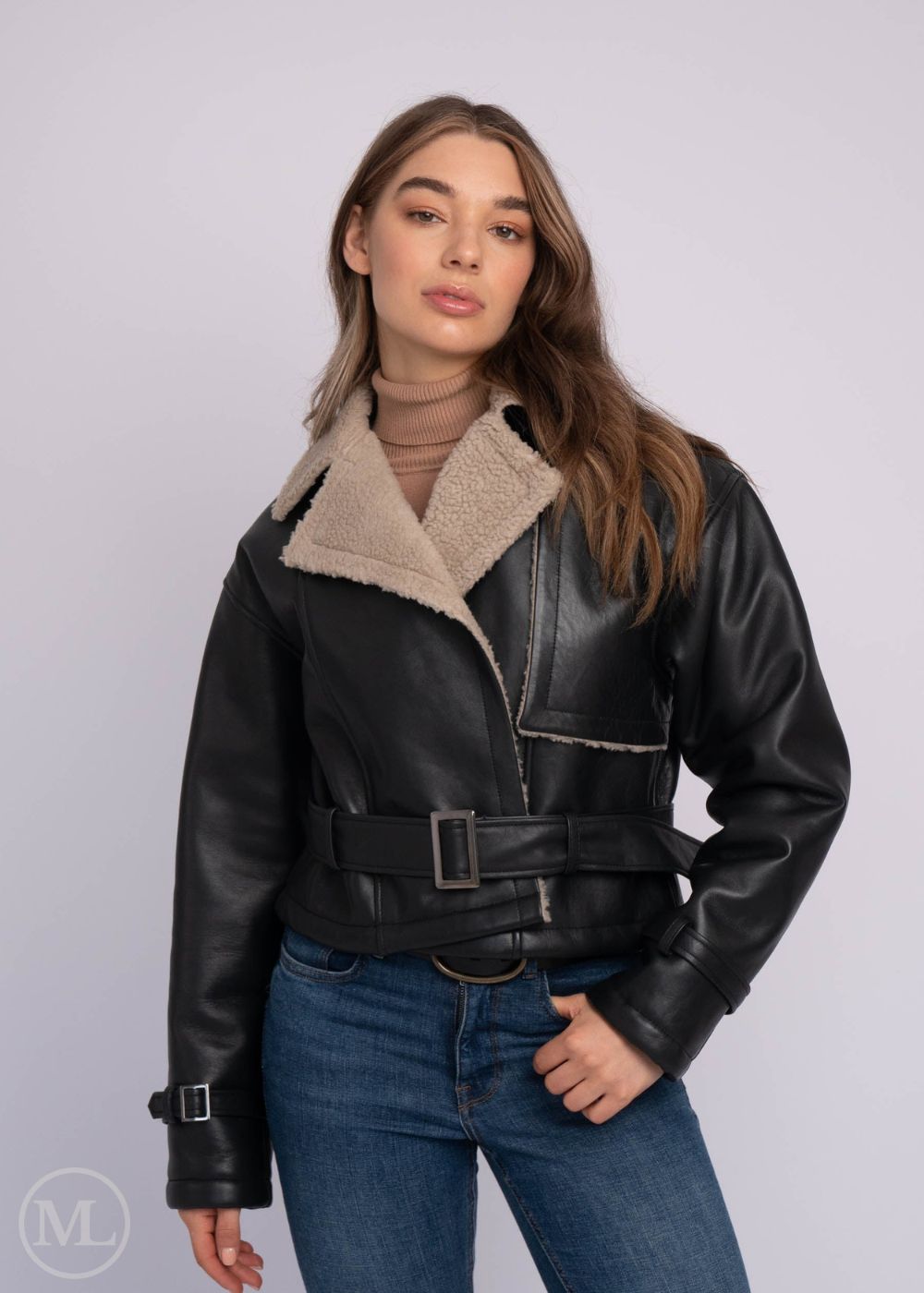 Woman wearing a black aviator leather jacket with a beige collar against a white background