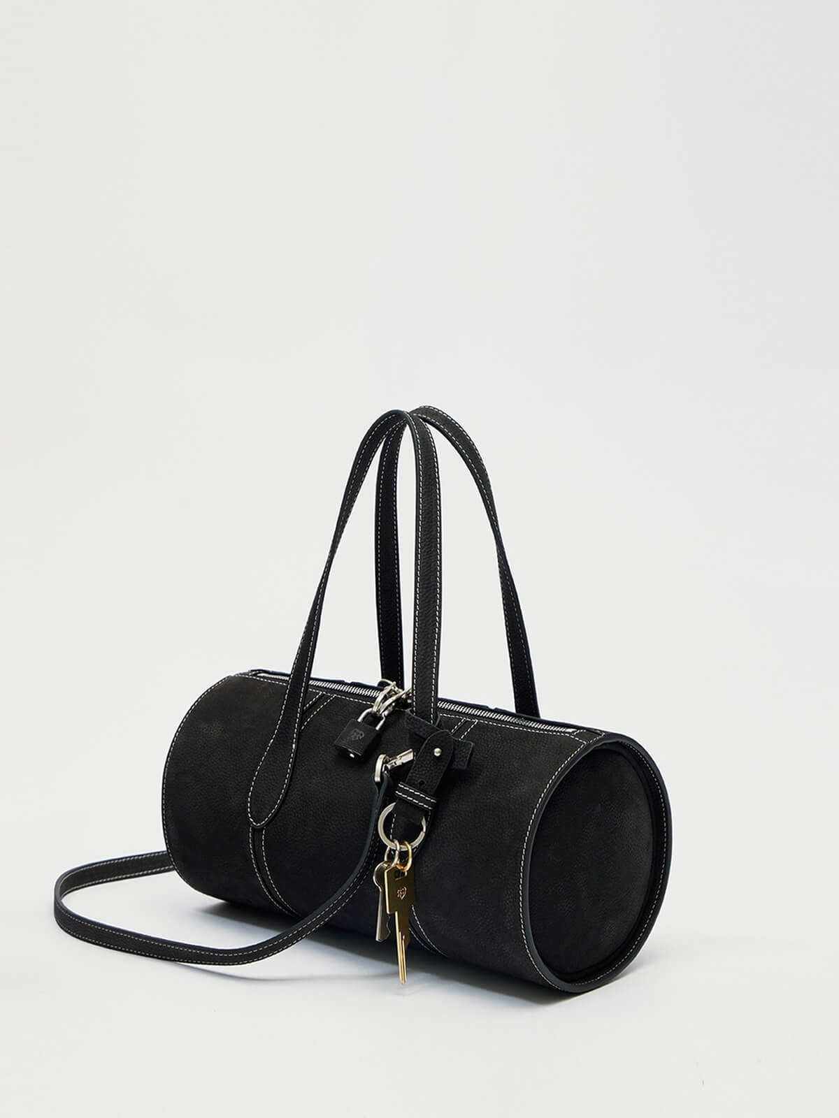 Black handbag with a strap on a light gray background
