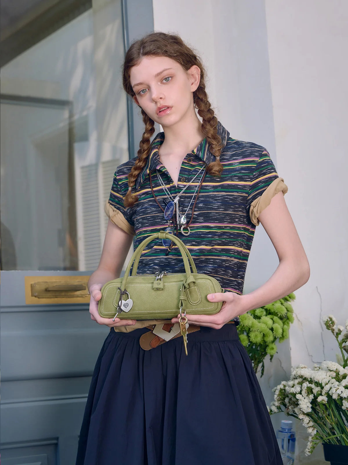Woman holding a green handbag in front of a building entrance