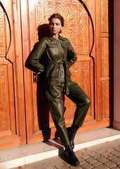 Woman in a olive khaki outfit standing in front of a wooden door with intricate carvings.