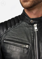 Close-up of a black leather biker jacket with zippers on a white background