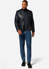 Man wearing a navy blue leather jacket, navy turtleneck, blue jeans, and black shoes on a white background